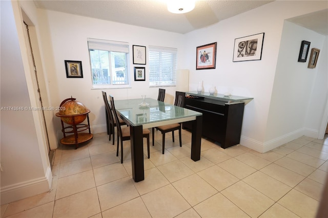 dining space with light tile patterned floors, baseboards, and a textured ceiling