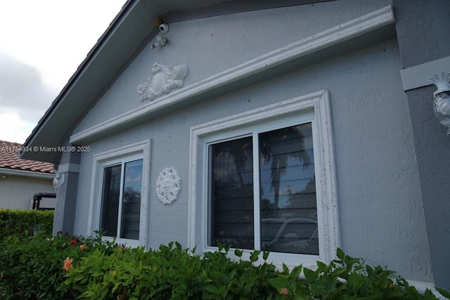 view of side of property featuring a tile roof and stucco siding