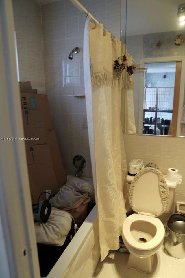 bathroom with toilet, tile walls, decorative backsplash, and shower / bath combination with curtain