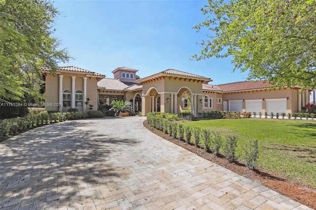 mediterranean / spanish house with a front yard, driveway, and stucco siding