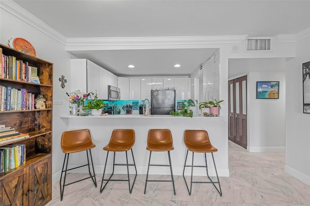 kitchen featuring visible vents, marble finish floor, a breakfast bar, and freestanding refrigerator