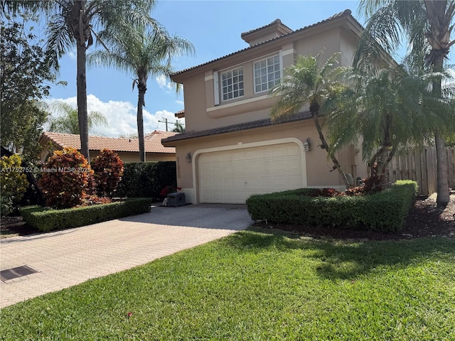 mediterranean / spanish home with stucco siding, an attached garage, fence, decorative driveway, and a front yard