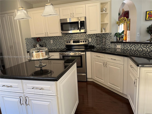 kitchen featuring dark countertops, dark wood-style flooring, stainless steel appliances, and decorative backsplash