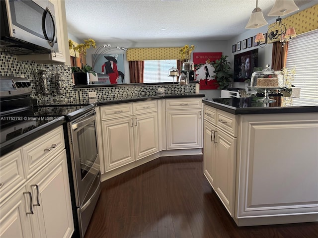 kitchen with dark wood-style floors, stainless steel appliances, dark countertops, backsplash, and a textured ceiling