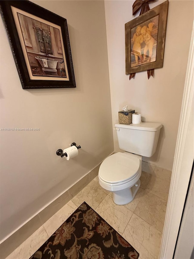 bathroom featuring marble finish floor, toilet, and baseboards