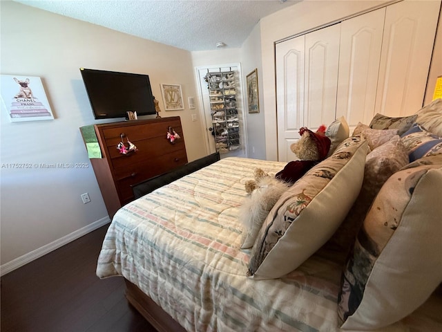 bedroom featuring a textured ceiling, baseboards, a closet, and wood finished floors