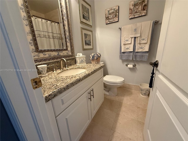 bathroom featuring toilet, curtained shower, baseboards, and vanity