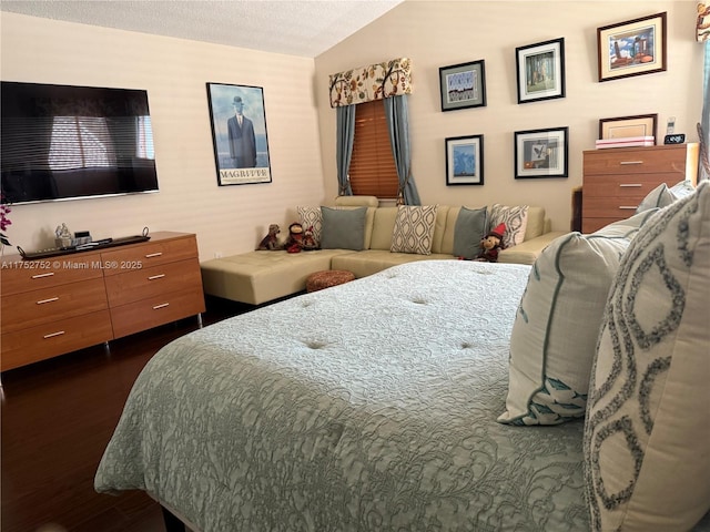 bedroom with vaulted ceiling and dark wood-style flooring