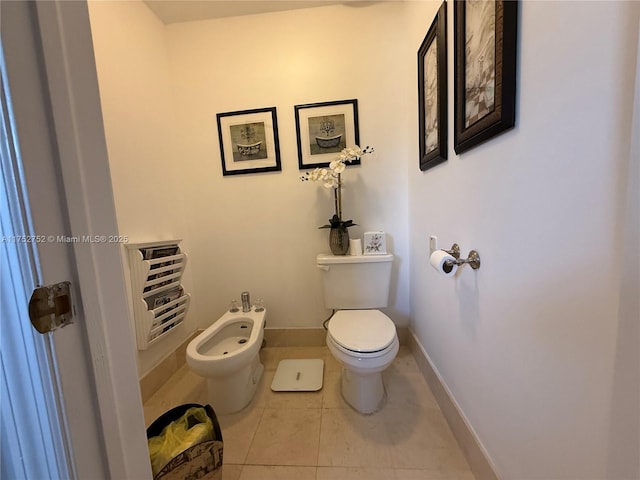 bathroom featuring toilet, tile patterned flooring, a bidet, and baseboards