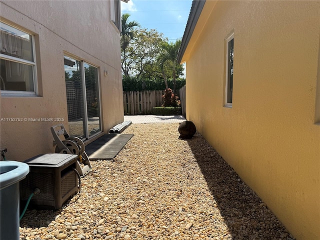 view of side of property featuring fence and stucco siding