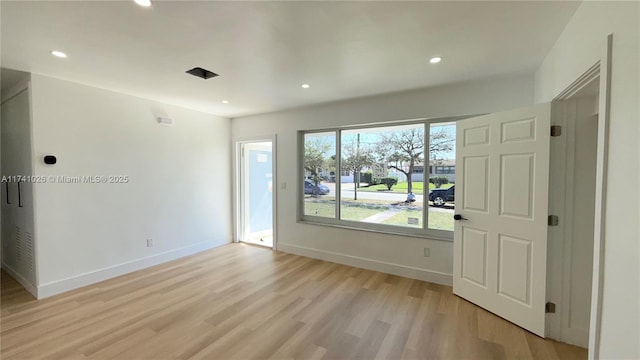 spare room featuring recessed lighting, baseboards, and light wood finished floors