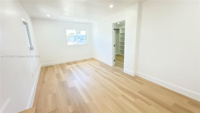 unfurnished bedroom featuring light wood finished floors, recessed lighting, a closet, a spacious closet, and baseboards