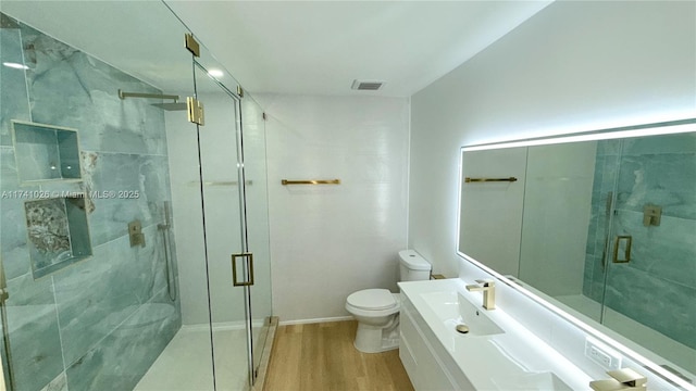 bathroom with a marble finish shower, visible vents, toilet, and wood finished floors