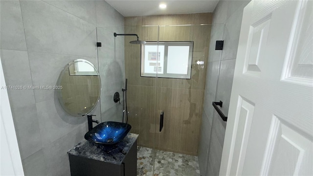 bathroom with vanity, walk in shower, and tile walls