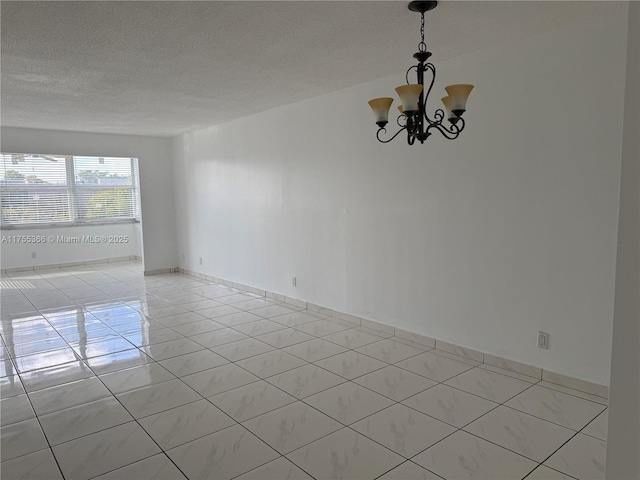 unfurnished room with a chandelier, light tile patterned flooring, a textured ceiling, and baseboards