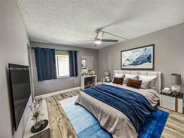 bedroom with a ceiling fan, baseboards, a textured ceiling, and light wood finished floors