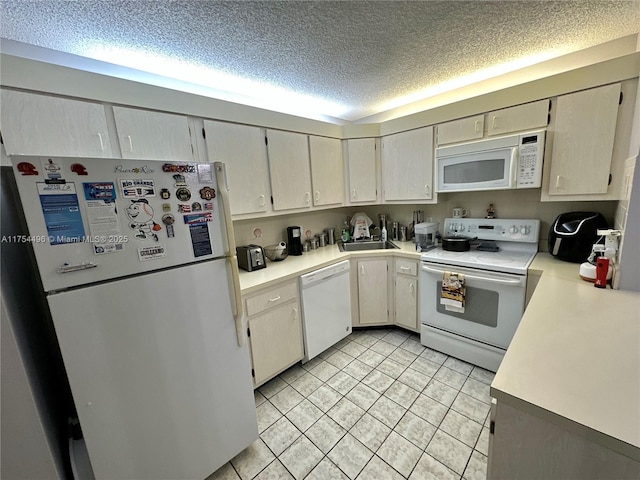 kitchen featuring white appliances, light countertops, a textured ceiling, and light tile patterned flooring