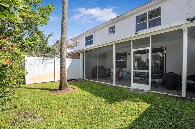 back of house featuring a patio, a lawn, fence, and a sunroom