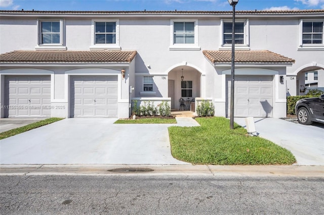 view of property with driveway, an attached garage, and stucco siding