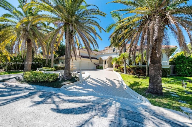 view of front of house featuring decorative driveway, a front yard, and stucco siding