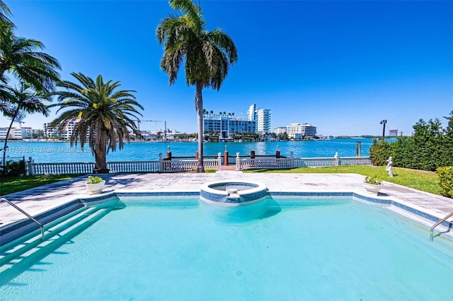 view of swimming pool featuring a water view, fence, and a pool with connected hot tub