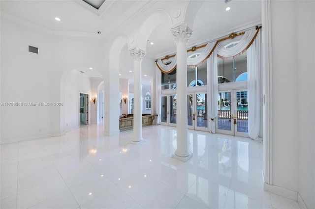 interior space featuring decorative columns, a towering ceiling, and ornamental molding