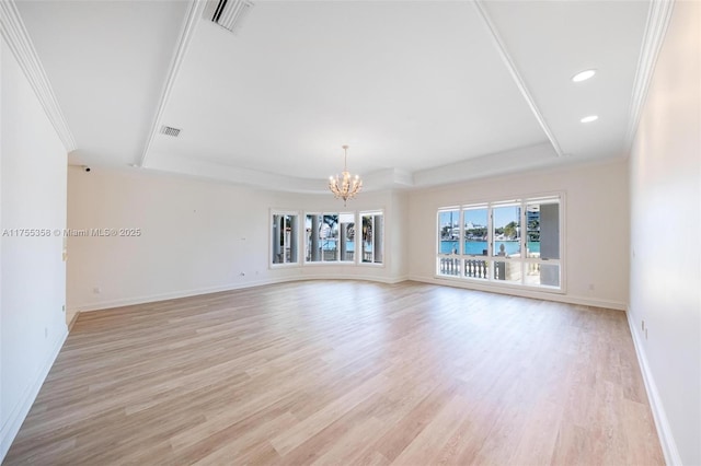 spare room featuring a tray ceiling, baseboards, visible vents, and light wood-style flooring