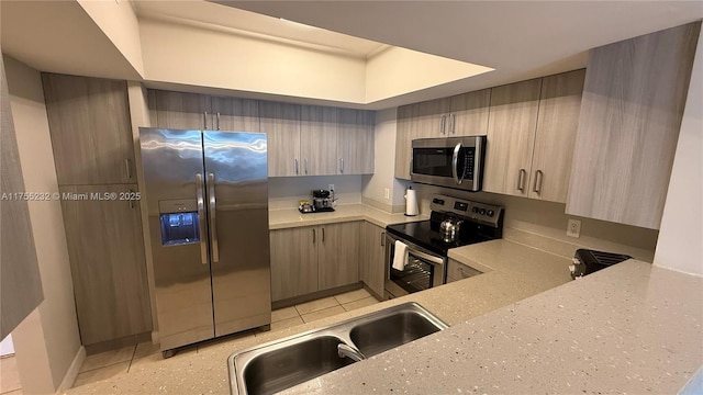 kitchen with light tile patterned floors, light stone counters, stainless steel appliances, and a sink