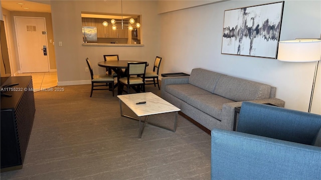 living room with a chandelier, baseboards, and wood finished floors