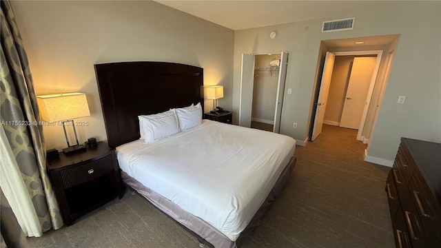 bedroom with baseboards, visible vents, dark wood finished floors, and a closet