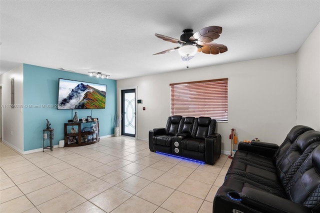 living area with light tile patterned floors, a textured ceiling, a ceiling fan, and baseboards