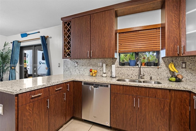 kitchen with light tile patterned floors, a peninsula, a sink, stainless steel dishwasher, and decorative backsplash