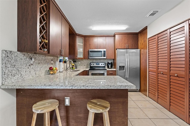 kitchen with light tile patterned floors, visible vents, a sink, stainless steel appliances, and backsplash