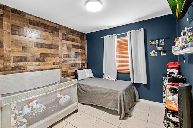 bedroom featuring tile patterned flooring, wooden walls, an accent wall, and baseboards