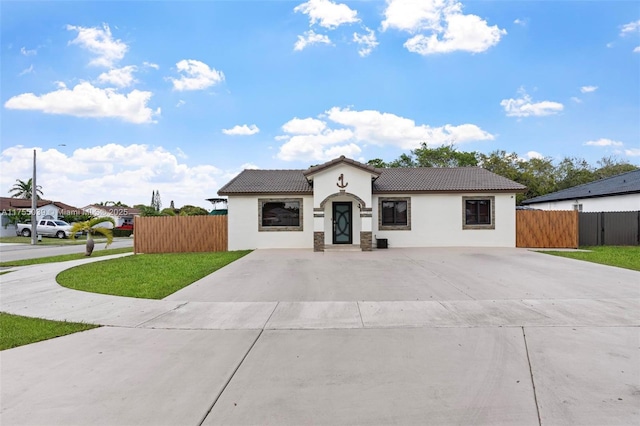 mediterranean / spanish home with a front yard, fence, a tile roof, and stucco siding