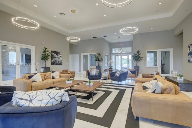 living area with a tray ceiling, french doors, a high ceiling, and visible vents