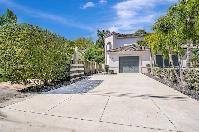 view of side of home featuring stucco siding, concrete driveway, an attached garage, fence, and a tiled roof