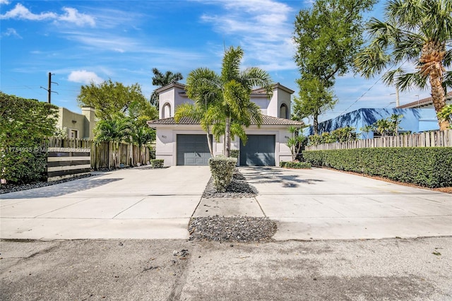 view of front of property featuring a tiled roof, fence, concrete driveway, and stucco siding