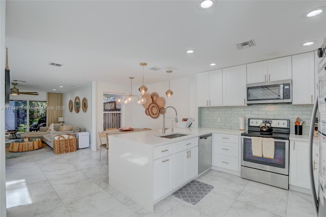 kitchen with a peninsula, appliances with stainless steel finishes, a sink, and visible vents