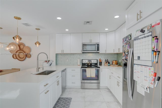 kitchen with visible vents, decorative backsplash, appliances with stainless steel finishes, a sink, and a peninsula