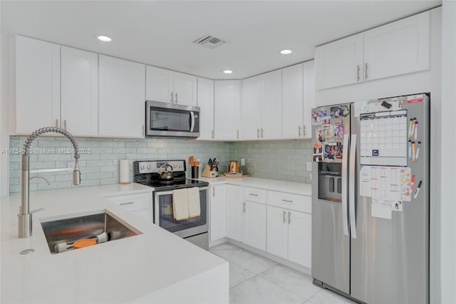 kitchen with stainless steel appliances, white cabinets, visible vents, and a sink