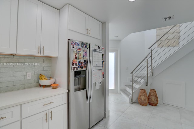 kitchen featuring stainless steel fridge, visible vents, decorative backsplash, light countertops, and white cabinetry