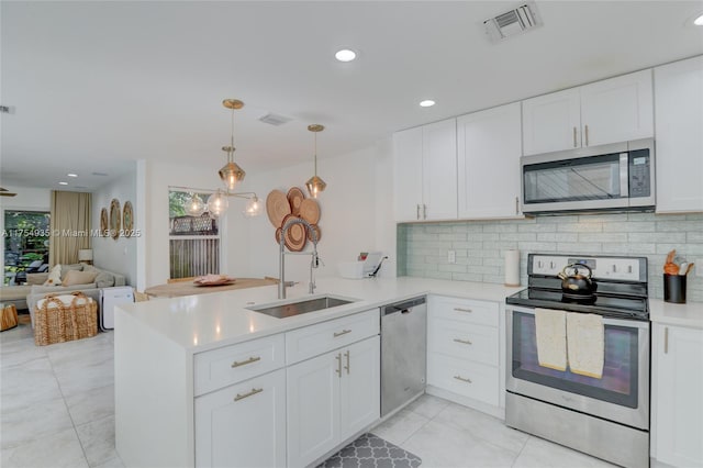 kitchen with visible vents, appliances with stainless steel finishes, a peninsula, light countertops, and a sink