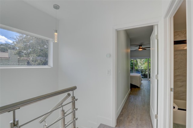 corridor featuring wood finished floors, an upstairs landing, and baseboards