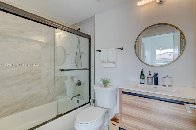 bathroom featuring toilet, combined bath / shower with glass door, and vanity