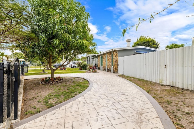 view of side of property with decorative driveway and fence