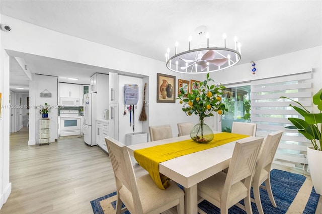 dining area with light wood-type flooring and a notable chandelier