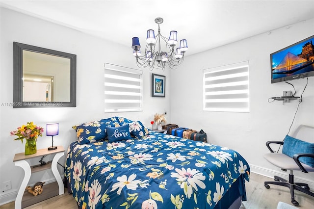 bedroom with baseboards, a chandelier, and wood finished floors