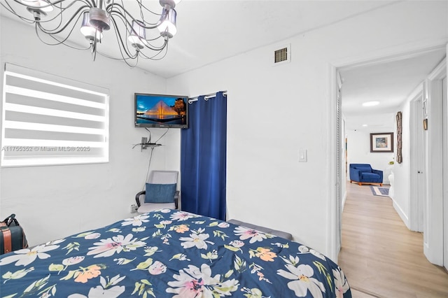 bedroom featuring visible vents, an inviting chandelier, and wood finished floors