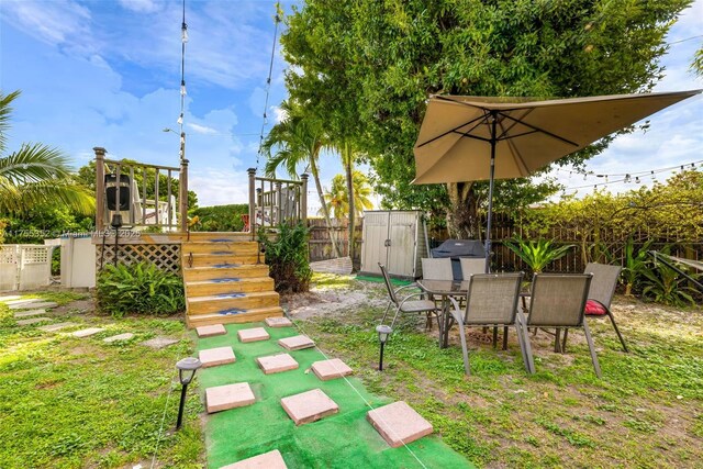 view of yard featuring fence, a storage unit, outdoor dining area, and an outdoor structure